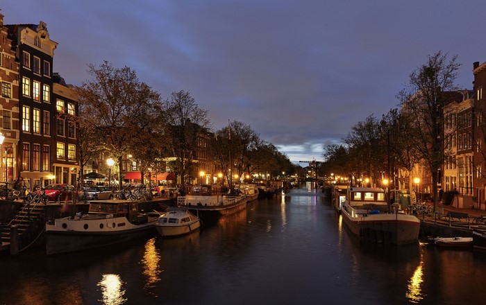 Amsterdam canal at dusk with houseboats and street lights