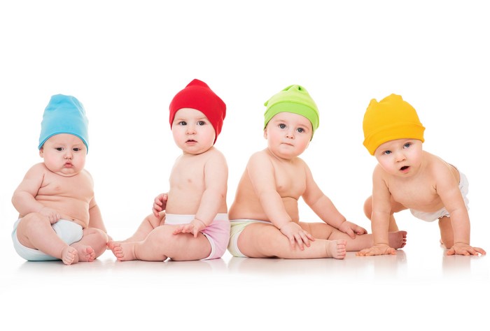 Four babies wearing colorful winter hats on a white background