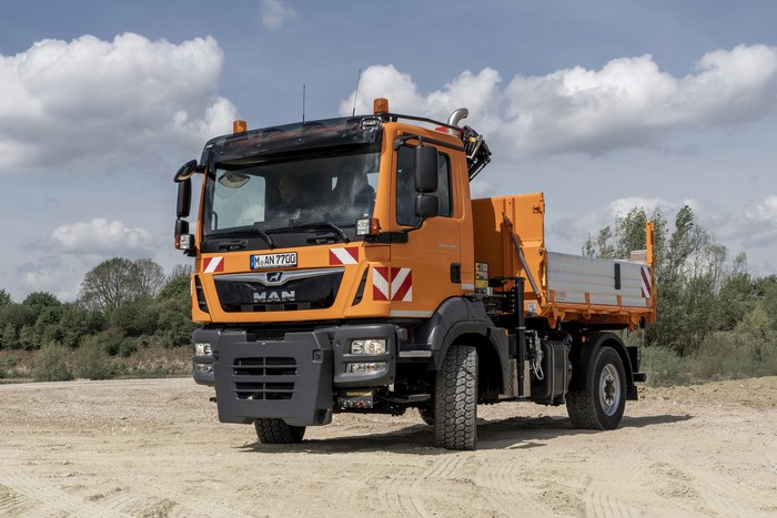 Orange MAN construction truck on a dirt road