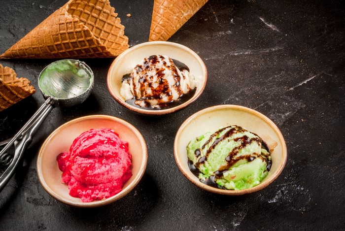 Three bowls of ice cream with waffle cones and scoop