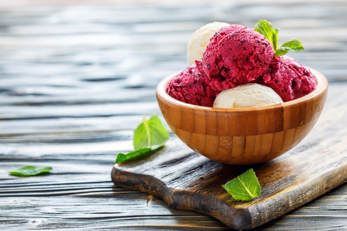 Ice cream scoops in a wooden bowl on a cutting board