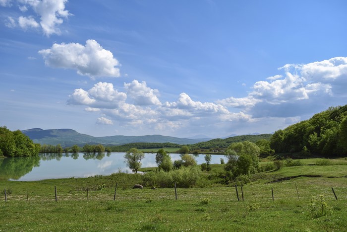 Lake and hills with green grass and blue sky