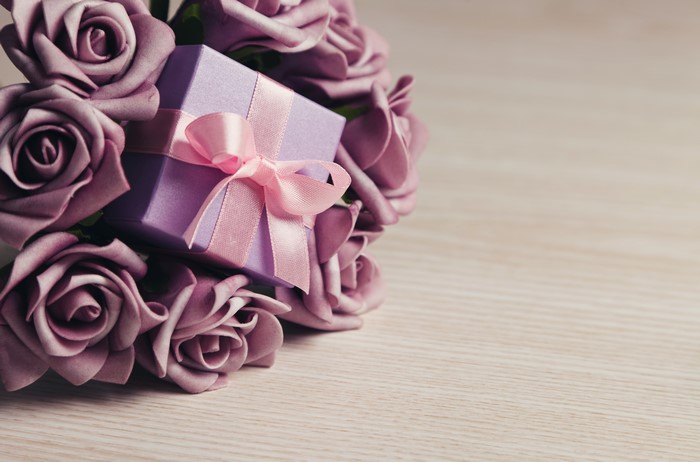 Purple roses and a gift box with a pink bow
