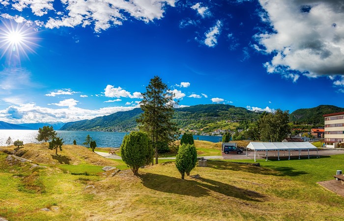 Sunny day by a lake with mountains and buildings