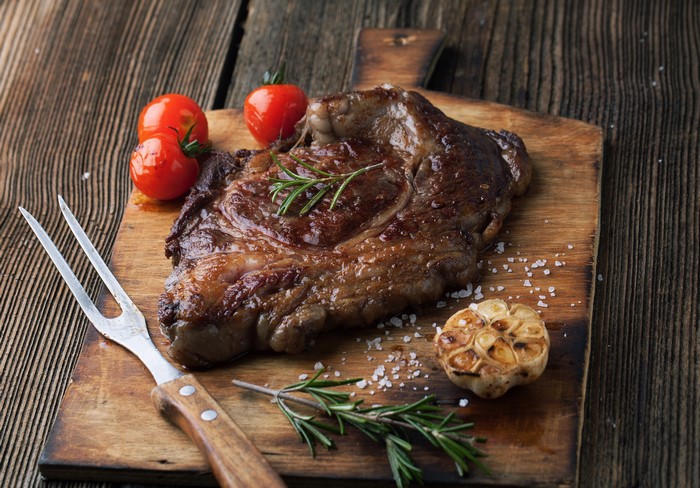 Steak with Tomatoes and Garlic on Cutting Board