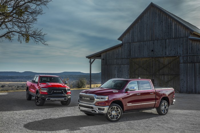 Two Ram 1500 pickup trucks parked near a barn