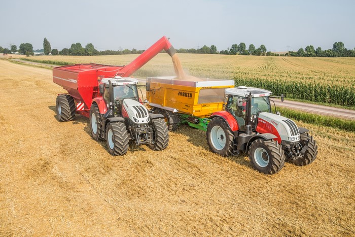 Two Steyr Tractors Harvesting Grain in a Field