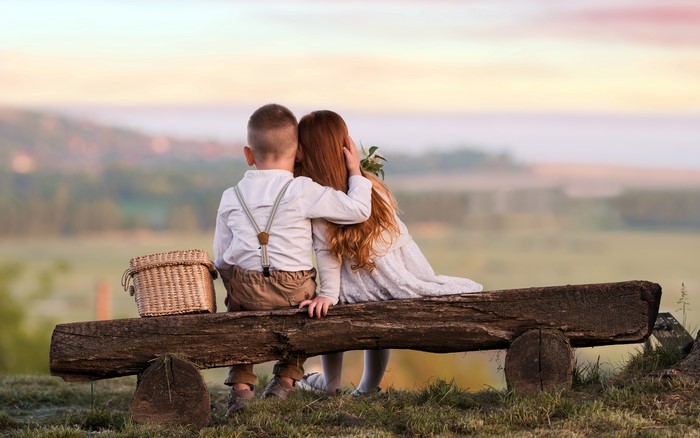 Tender Moment of Two Children Sitting on Wooden Bench