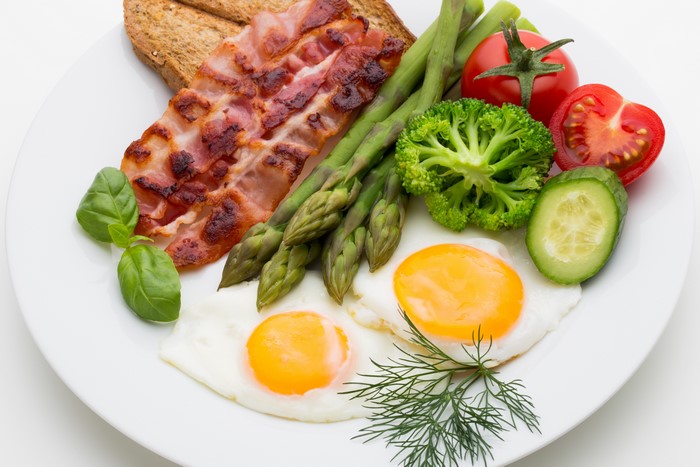 Fried eggs with bacon, toast, and vegetables