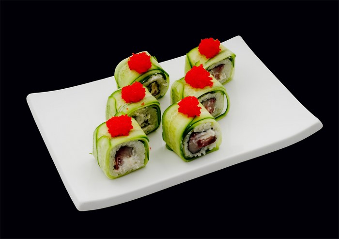 Sushi rolls with cucumber and red caviar on a white plate