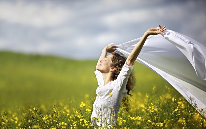 Woman with white cloth in a field of yellow flowers
