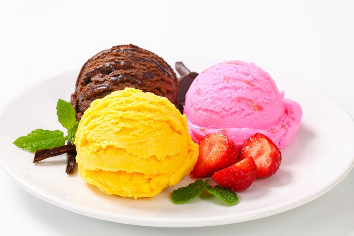 Three scoops of ice cream with strawberries and mint