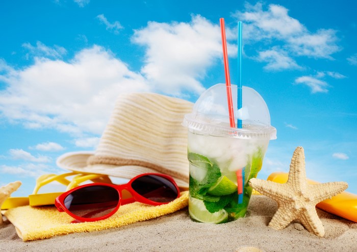 Beach scene with mojito, hat, sunglasses, and starfish