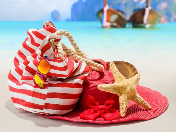 Beach bag, hat, sunglasses, and starfish on a beach