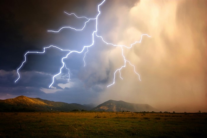Lightning strikes over hills and a field