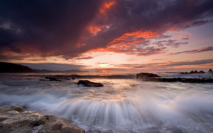 Ocean waves crashing on rocks at sunset