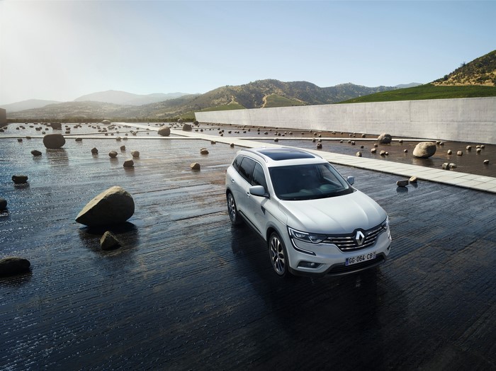White Renault Koleos SUV on a wet surface with rocks