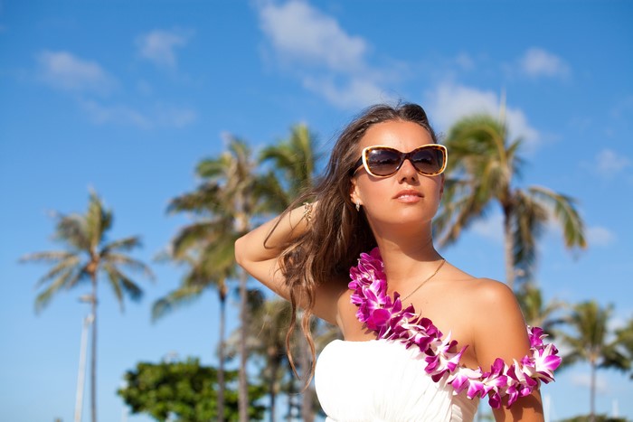 Woman with lei and sunglasses on beach