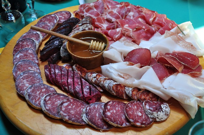 Charcuterie board with various cured meats and honey