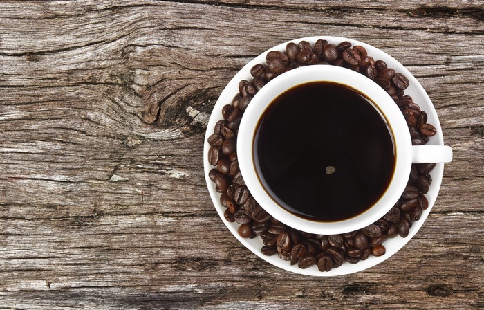 Coffee cup and beans on wood planks