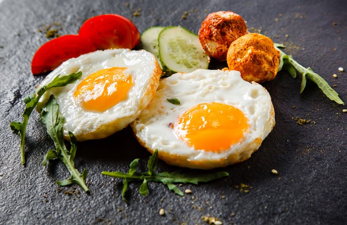 Fried eggs with tomatoes, cucumbers, and cheese balls