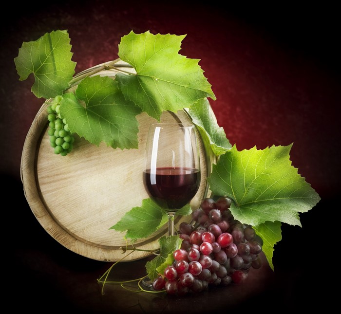 Wine barrel with grapes and glass of red wine