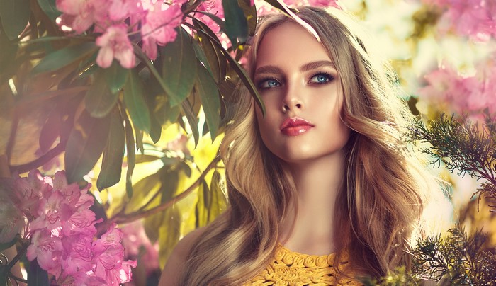 Blonde woman with blue eyes among pink flowers