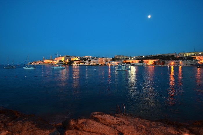 Valletta, Malta bay at night with moon and city lights