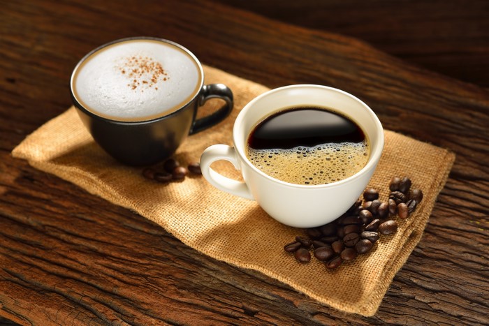Two cups of coffee and cappuccino with coffee beans