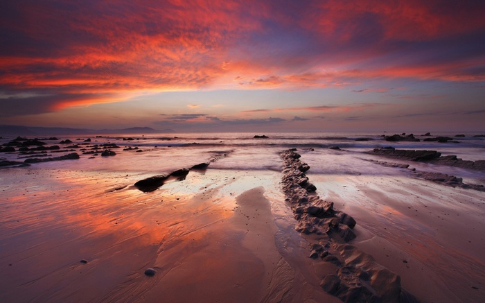 Sunset over a rocky beach with colorful clouds