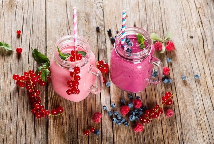 Two berry smoothies with fresh berries on wood