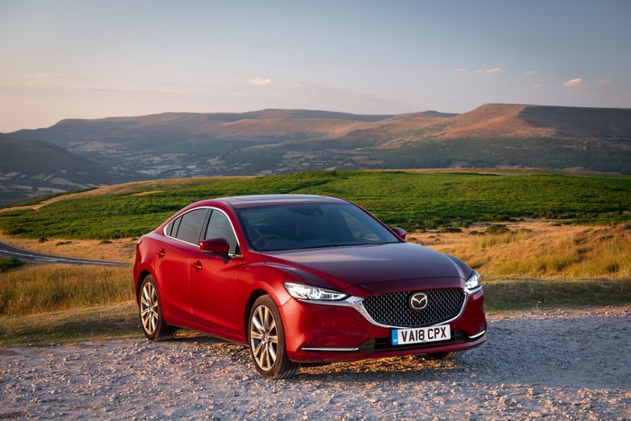 Red 2018 Mazda 6 parked on a gravel road with hills in the background