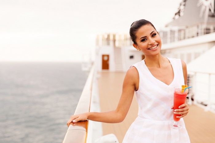 Woman in white dress holding a cocktail on a cruise ship deck