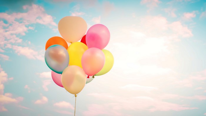 Colorful balloons floating in a cloudy sky