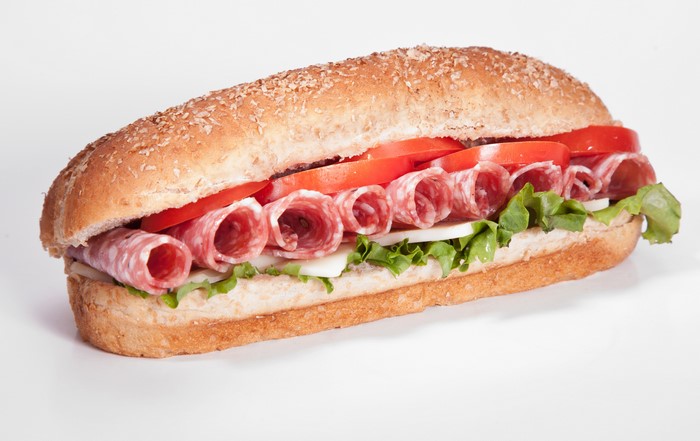 Sandwich with salami, tomatoes, lettuce, and cheese on a bun