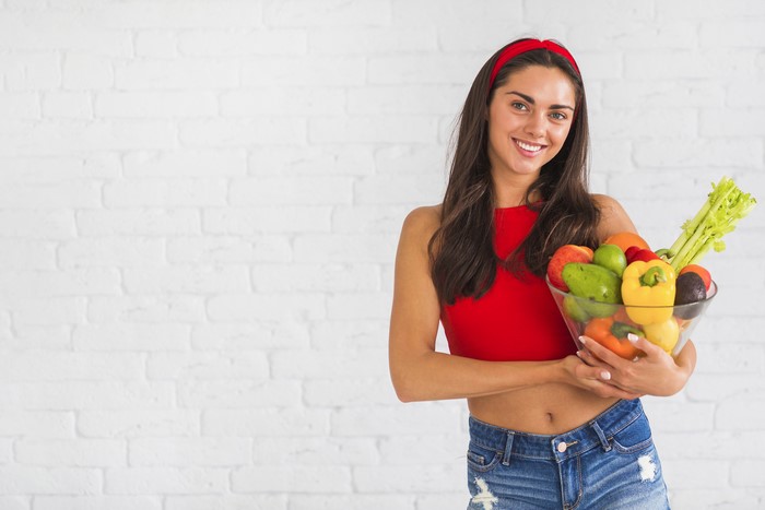 Woman holding a bowl of fruits and vegetables
