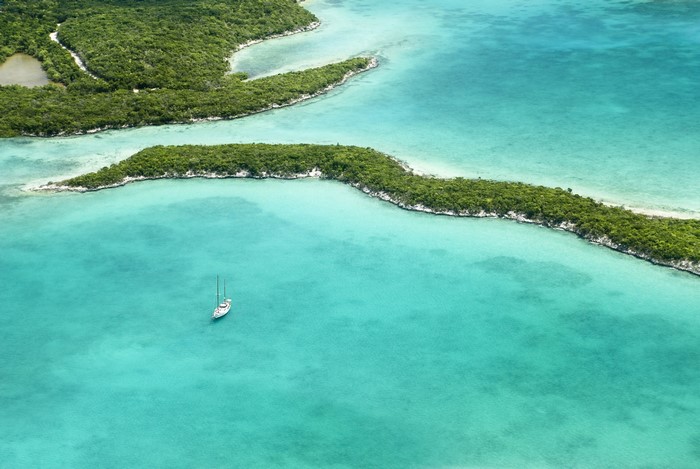 Aerial view of islands and turquoise water with a sailboat