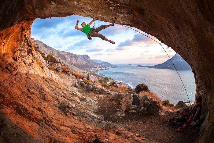 Man rock climbing in a cave overlooking the sea