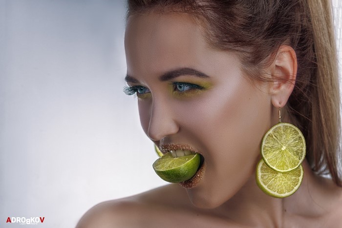 Woman with lime in mouth and lime earrings