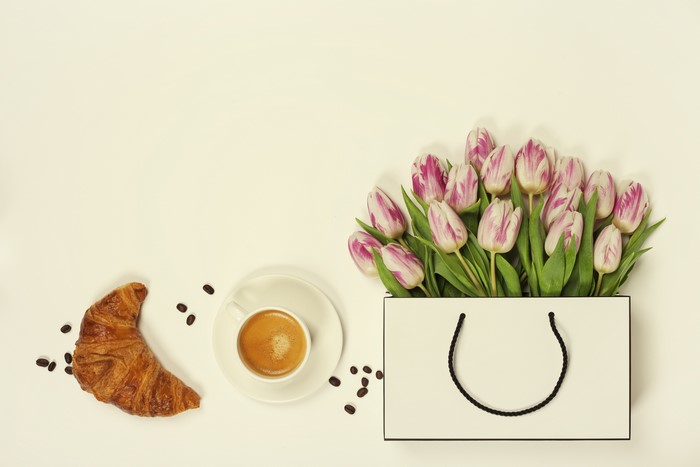 Tulips in a handbag with coffee and croissant