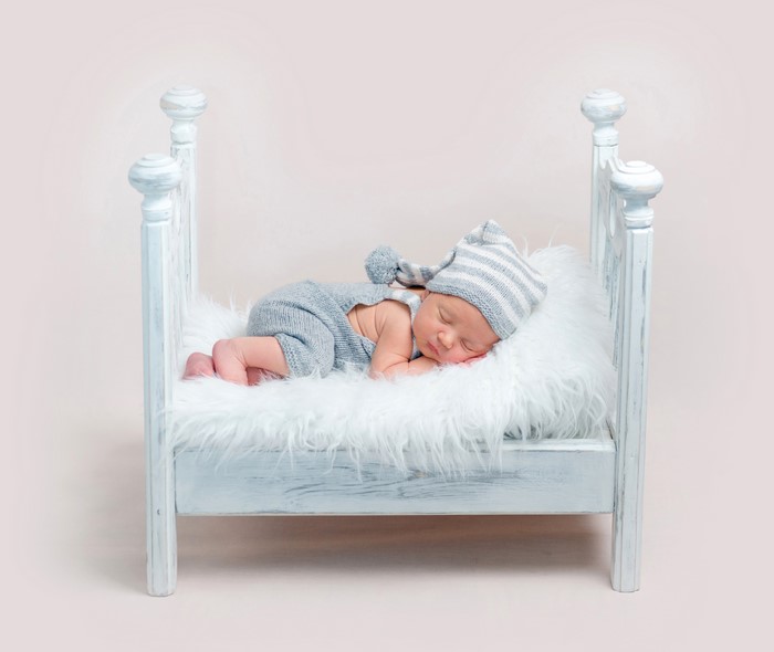 Newborn baby sleeping in a bed with a winter hat