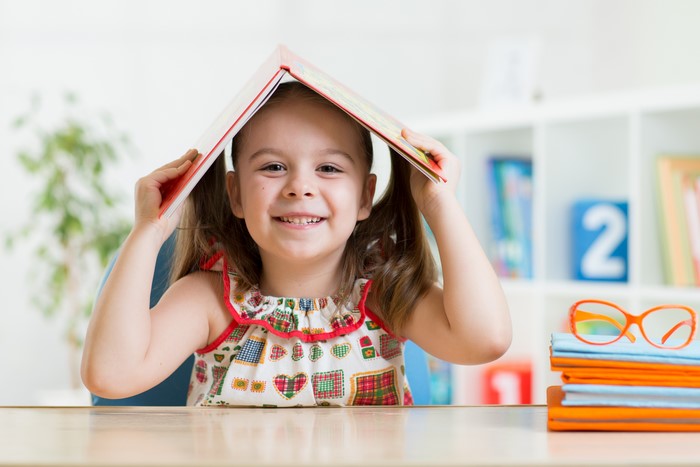Little girl with book over head