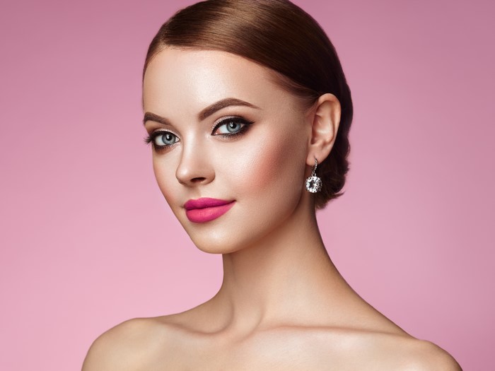 Woman with brown hair and pink lipstick wearing earrings