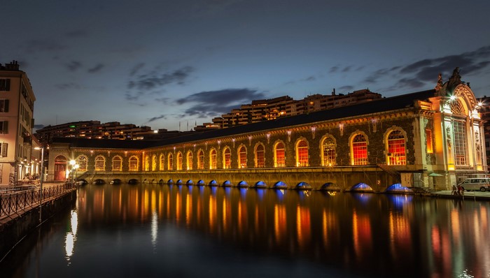 Building with arched windows reflected in water at night