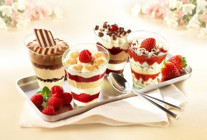 Four layered desserts with berries and chocolate on a tray