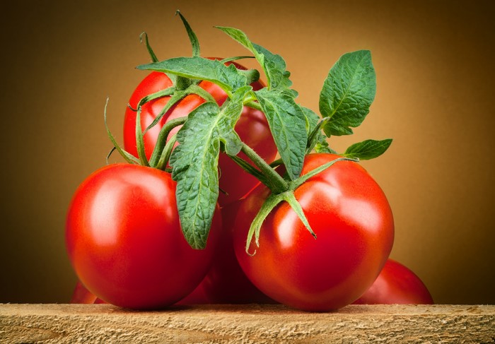 Tomatoes with Foliage on Wooden Surface
