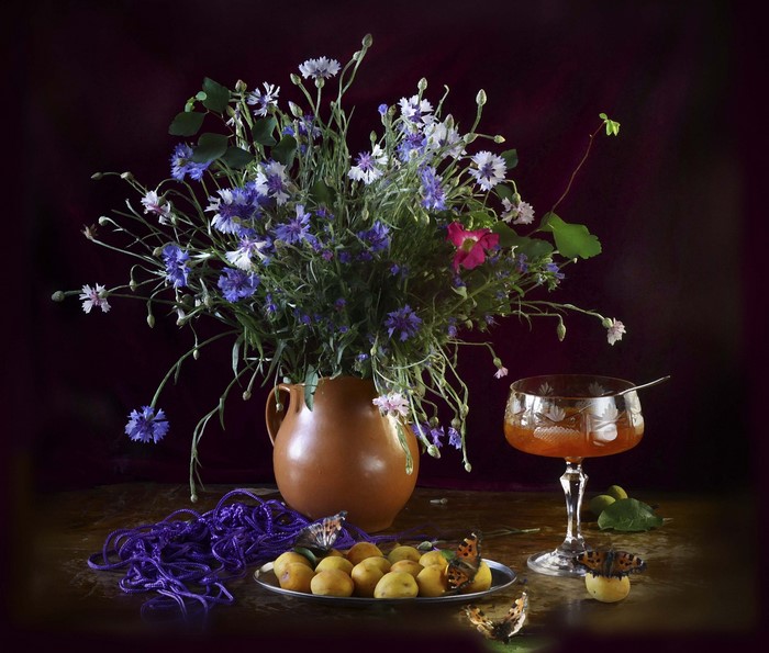 Still life with cornflowers, apricots, jam, and butterflies