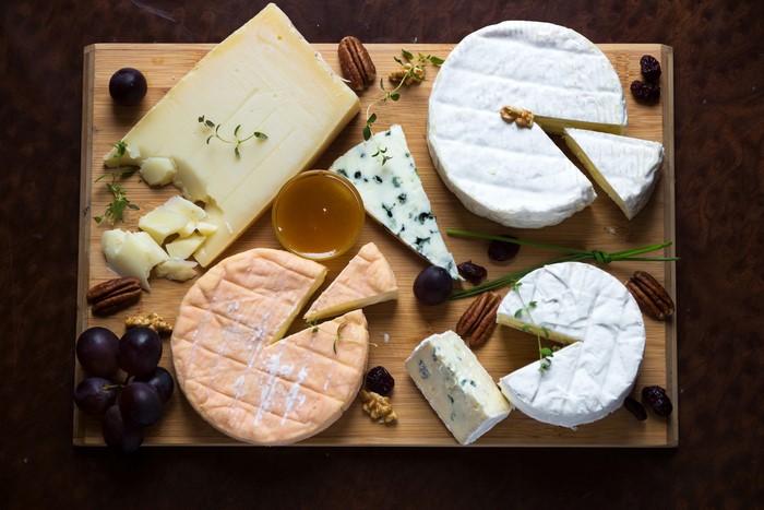Cheese board with grapes, nuts, and honey