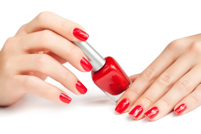 Hands with red nail polish holding nail polish bottle