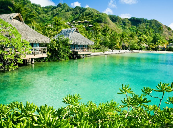 Overwater bungalows on a tropical island with lush green hills